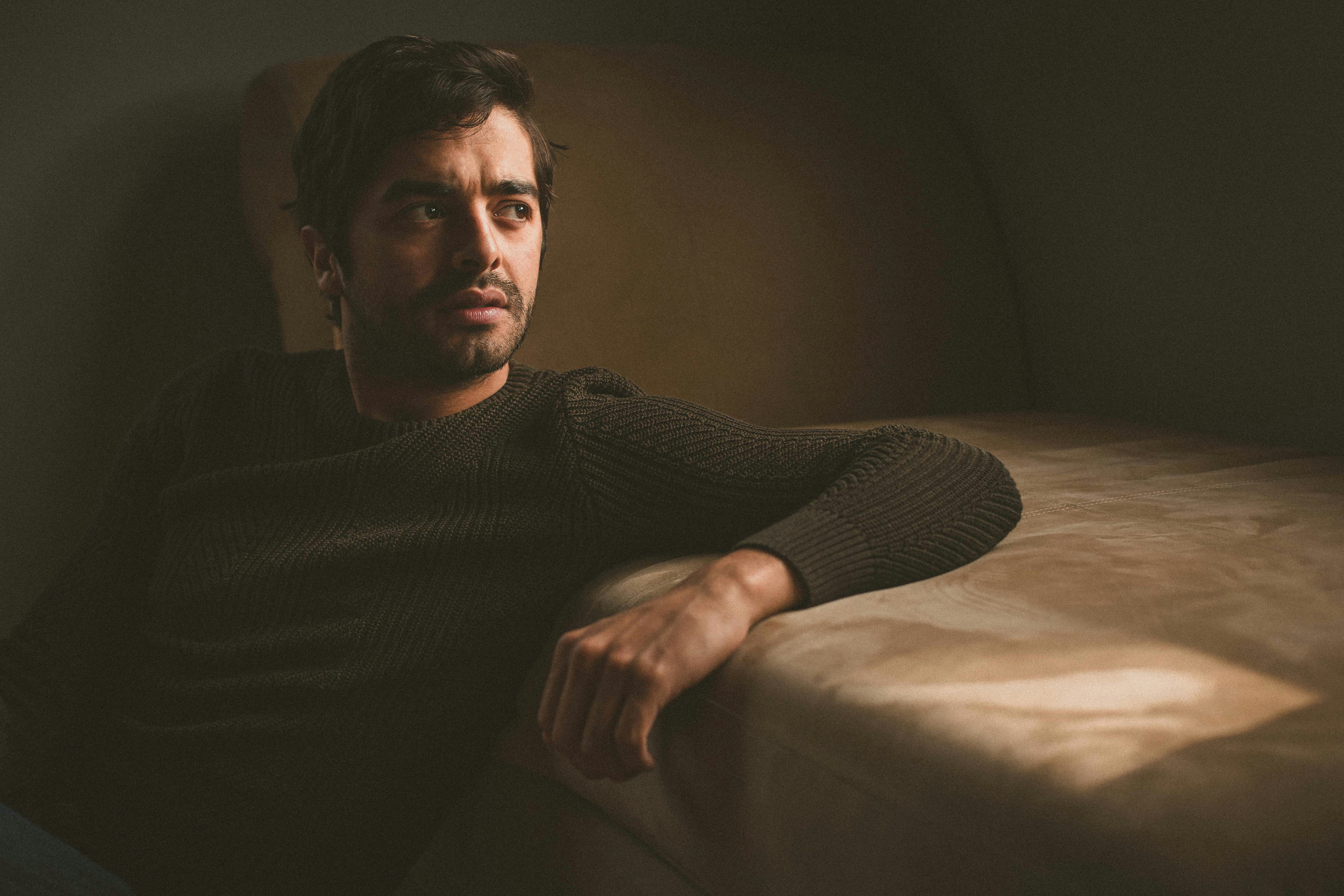 a man sitting on top of a couch next to a window
