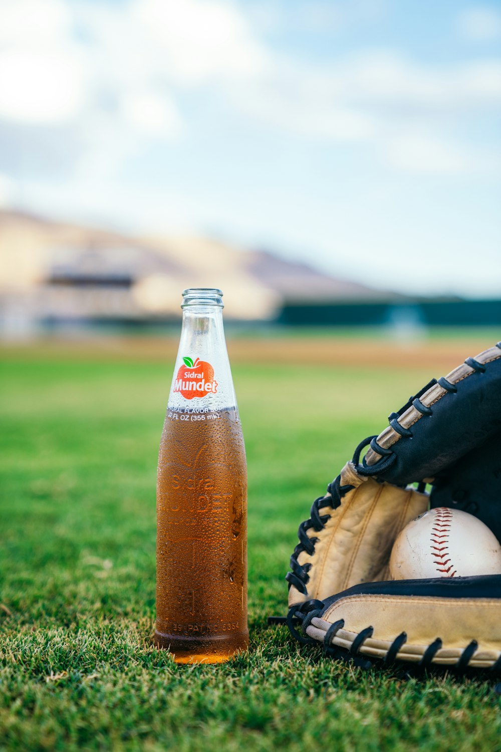 una botella de sidra de manzana junto a un guante de béisbol