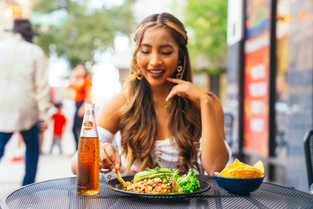 a woman sitting at a table with a plate of food