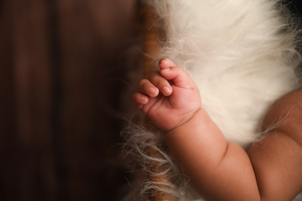 a close up of a baby's hand on a chair