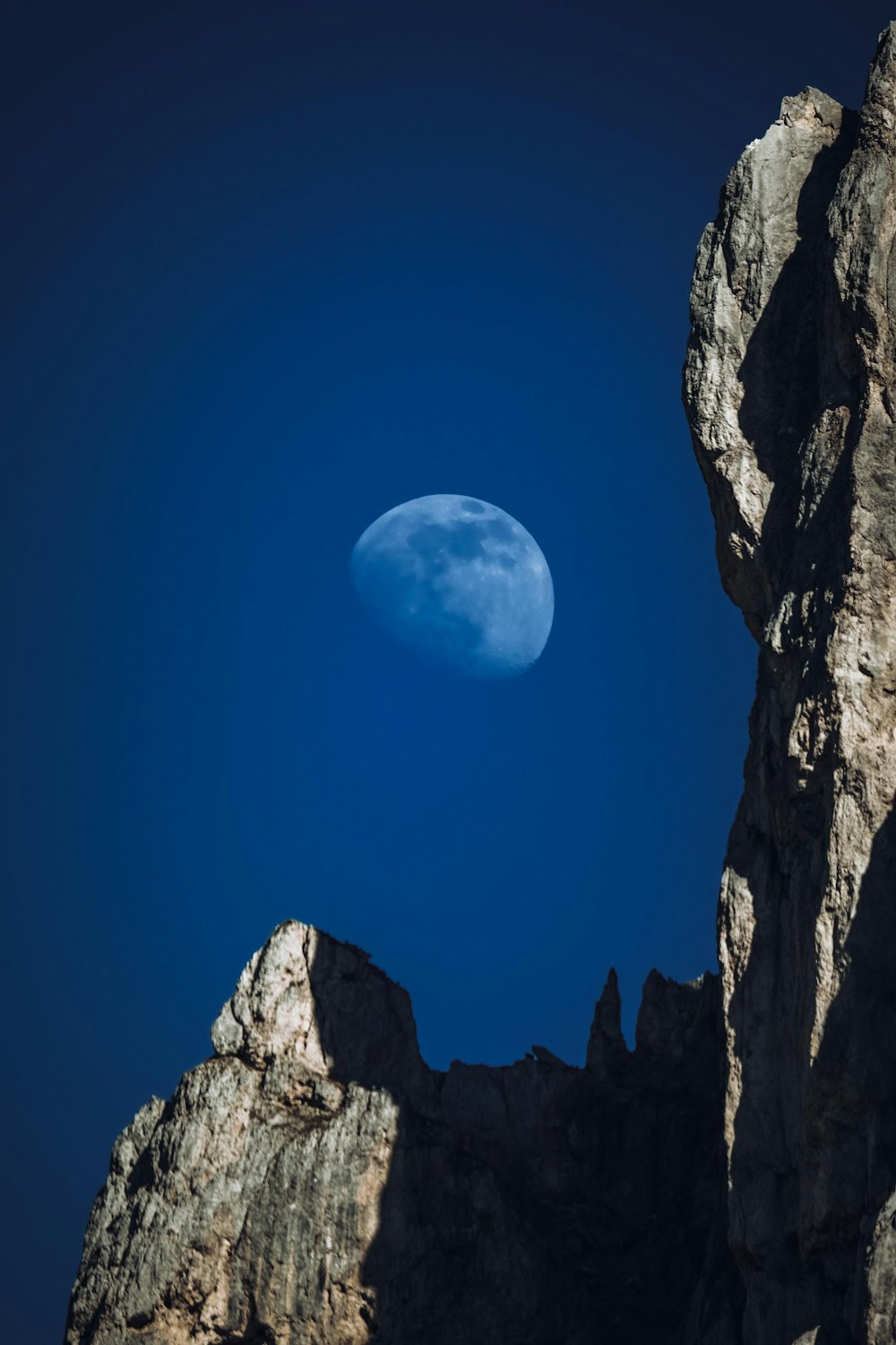 a full moon is seen in the sky above some rocks