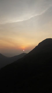 A scenic photograph of a sunset over mountains with a 'Click Here' button overlay