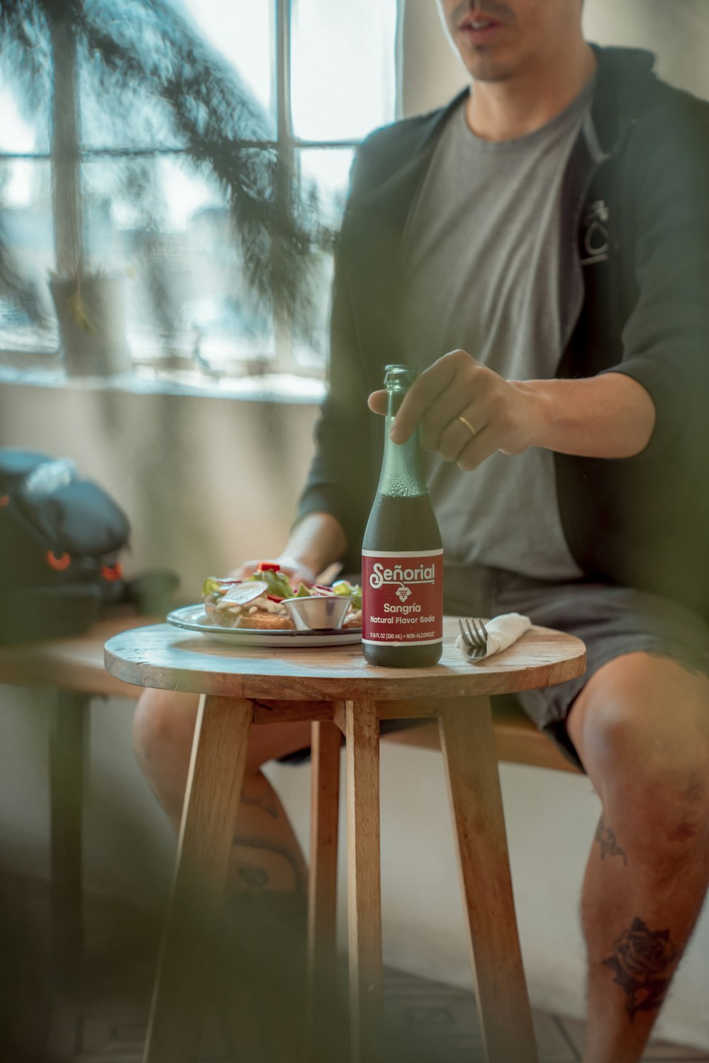 a man sitting at a table with a bottle of beer