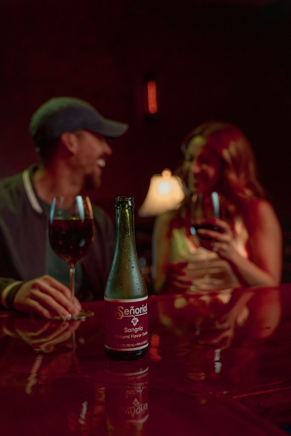 a man and a woman sitting at a table with a bottle of wine