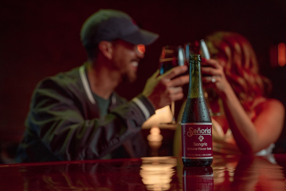 a man and a woman sitting at a table with a bottle of wine