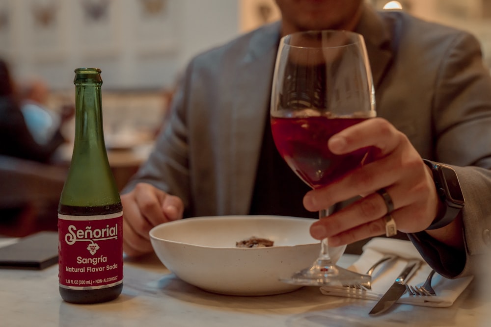 a man sitting at a table with a glass of wine