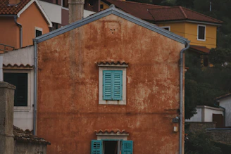 A modest home exterior with old stucco showing wear and discoloration.