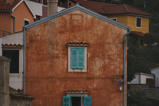 A modest home exterior with old stucco showing wear and discoloration.