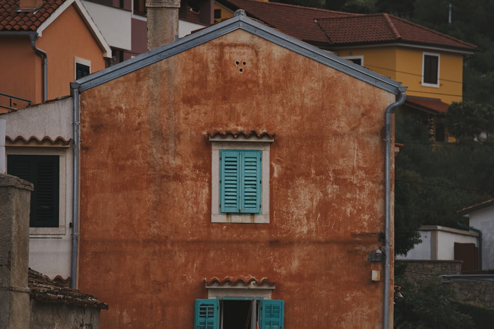 a brown building with a blue window and shutters