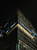 Aerial drone shot of a modern luxury skyscraper with glass and steel facade at dusk.