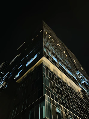Aerial drone shot of a modern luxury skyscraper with glass and steel facade at dusk.