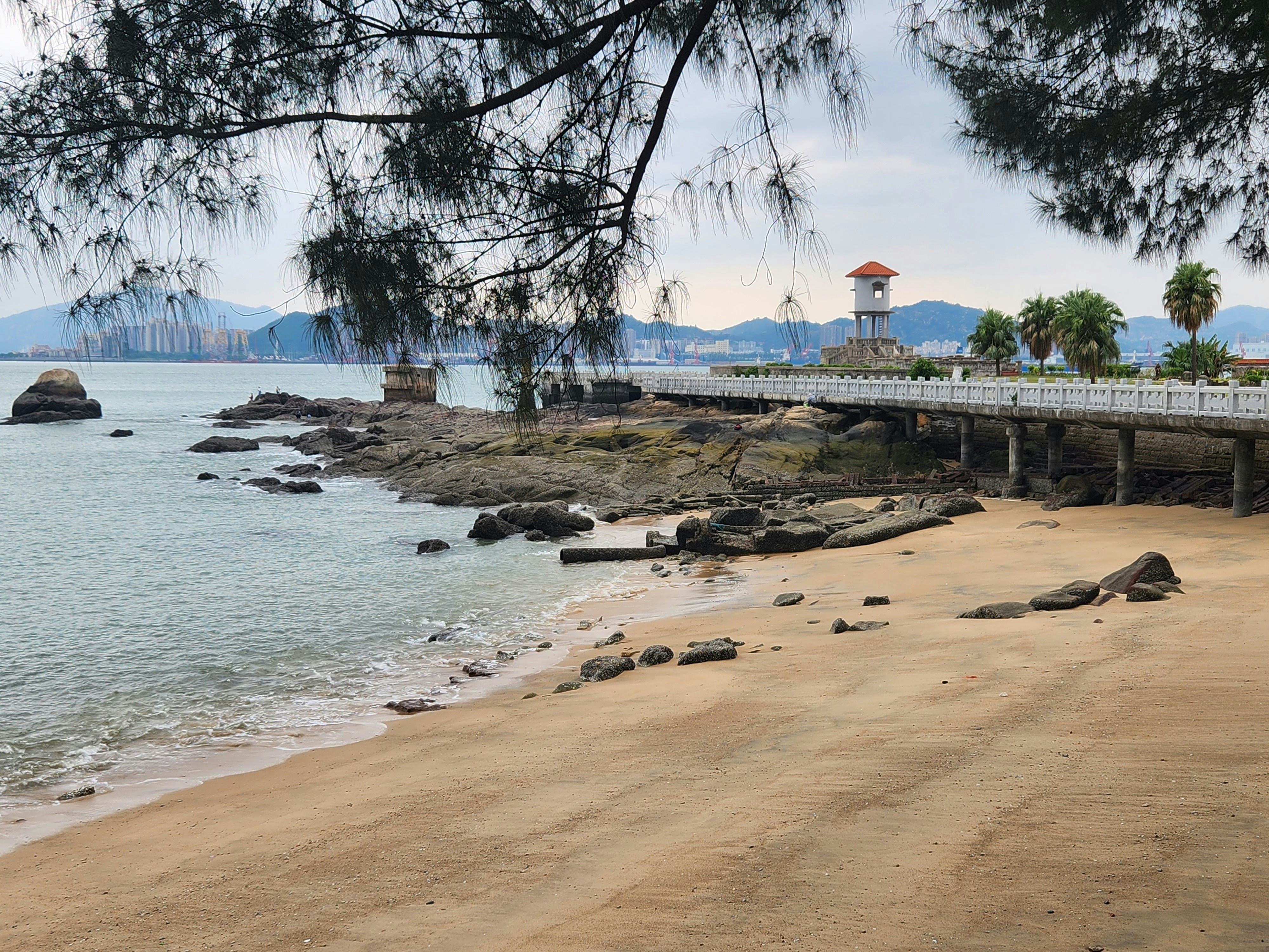 une vue d’une plage avec un pont en arrière-plan