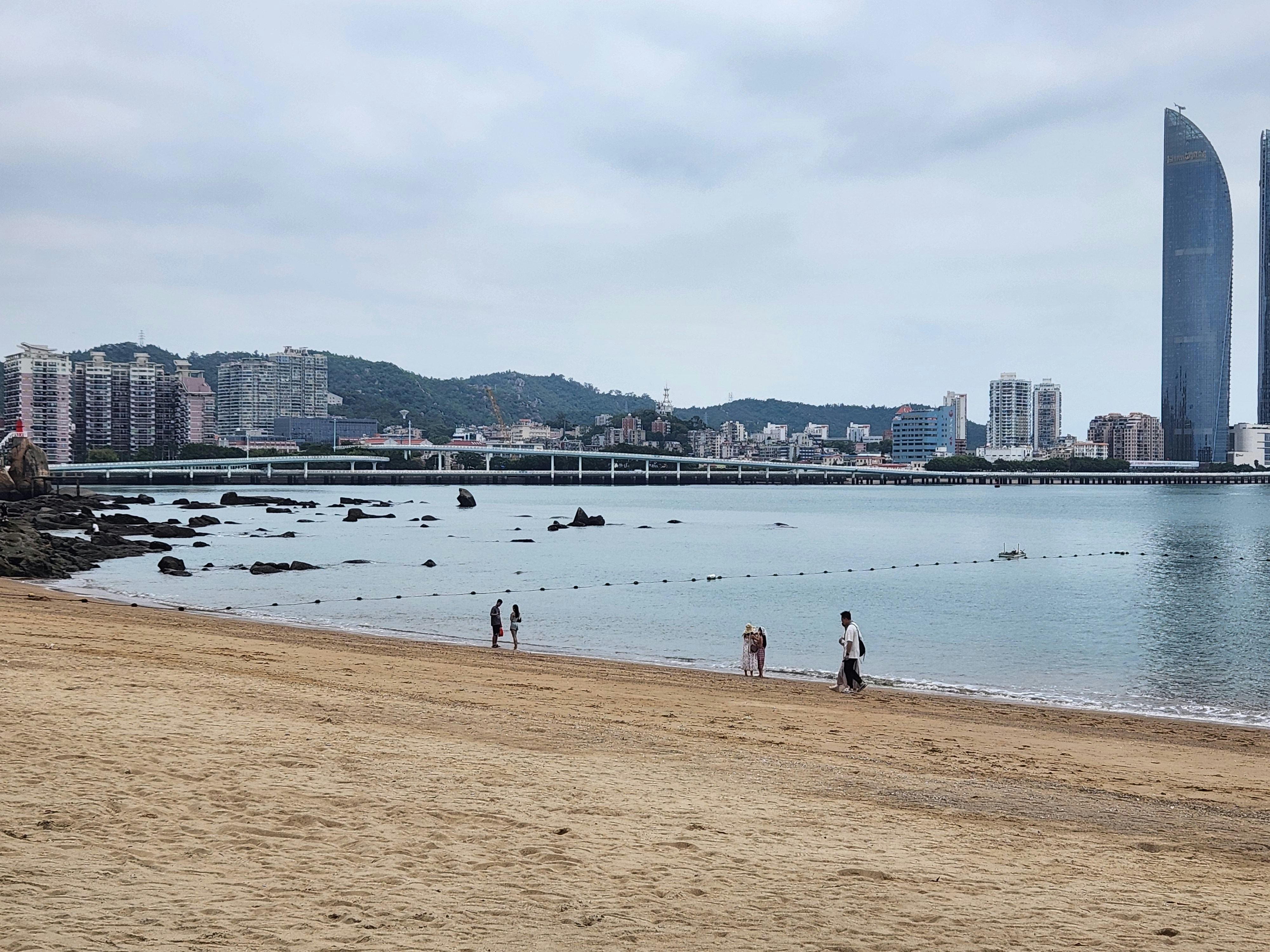 un groupe de personnes debout au sommet d’une plage de sable