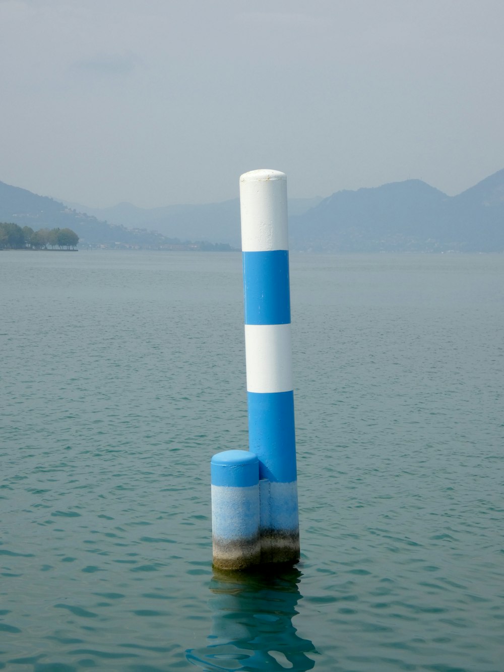 un poteau bleu et blanc sortant de l’eau