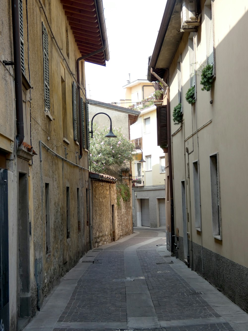 a narrow alley with a lamp on the side
