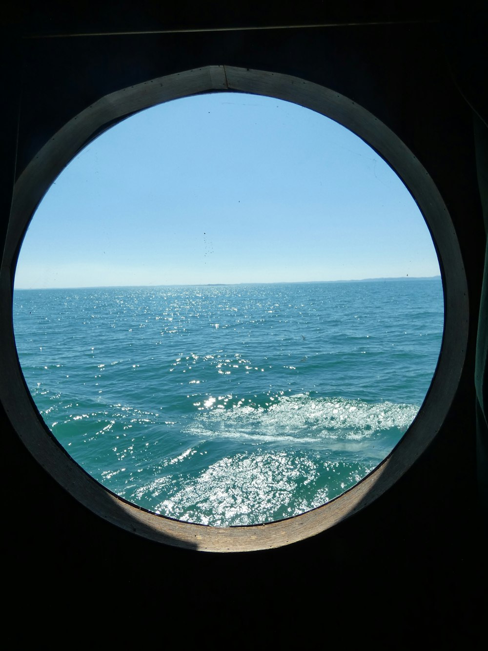 a view of the ocean through a porthole window