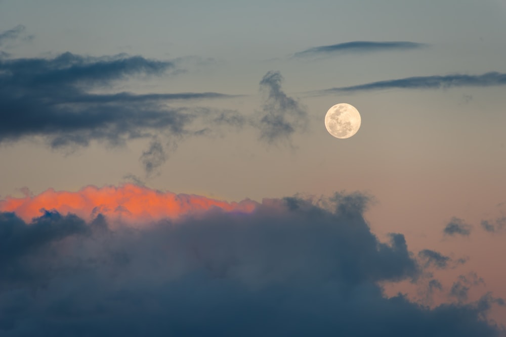 a full moon is seen through the clouds