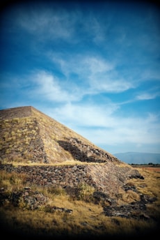 a very tall pyramid sitting on top of a dry grass field