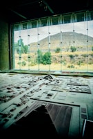 A detailed architectural model is displayed in the foreground, representing a complex of ancient structures and layout. Large windows in the background reveal a pyramid and natural landscape with trees and shrubs, bathed in daylight.