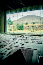 A detailed architectural model is displayed in the foreground, representing a complex of ancient structures and layout. Large windows in the background reveal a pyramid and natural landscape with trees and shrubs, bathed in daylight.