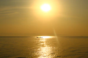 A serene sunset over a calm lake with a small boat drifting, evoking peaceful reflection.