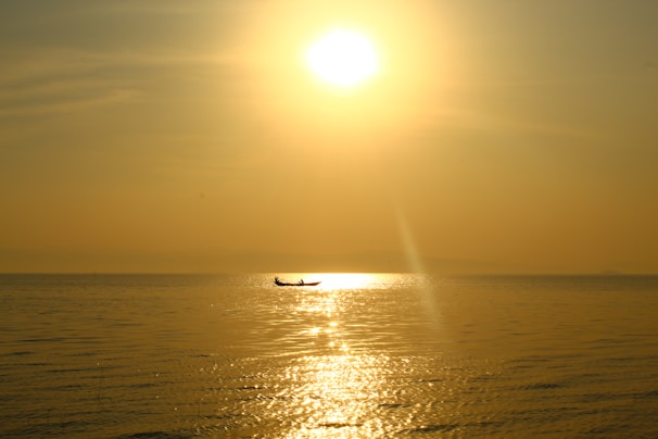 An artistic image of a serene boat floating on calm waters at sunset.