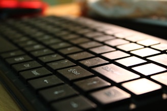 Close-up of hands typing on a keyboard with a soft-focus background of design tools.