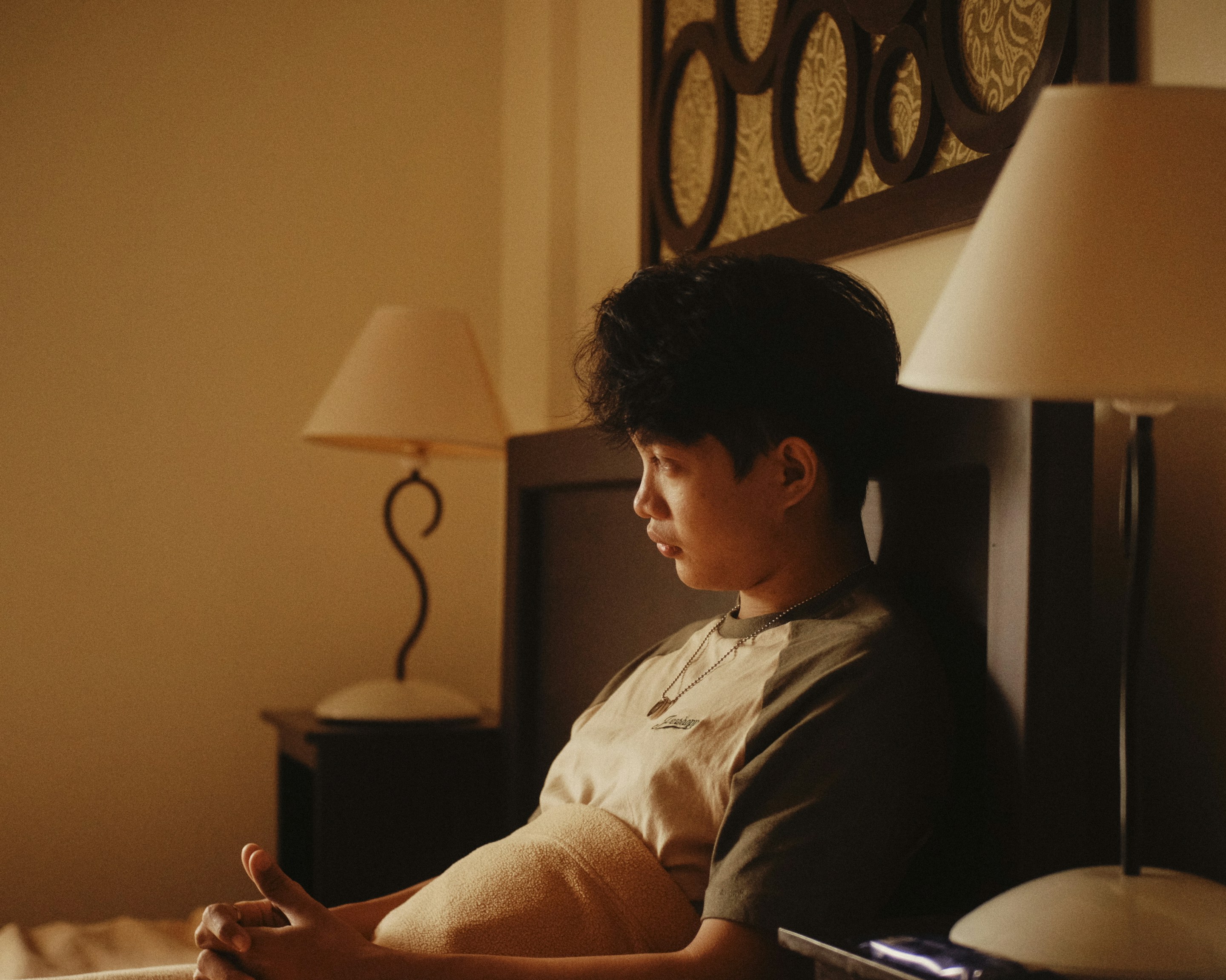 Ein junger Mann sitzt auf einem Bett in einem Hotelzimmer