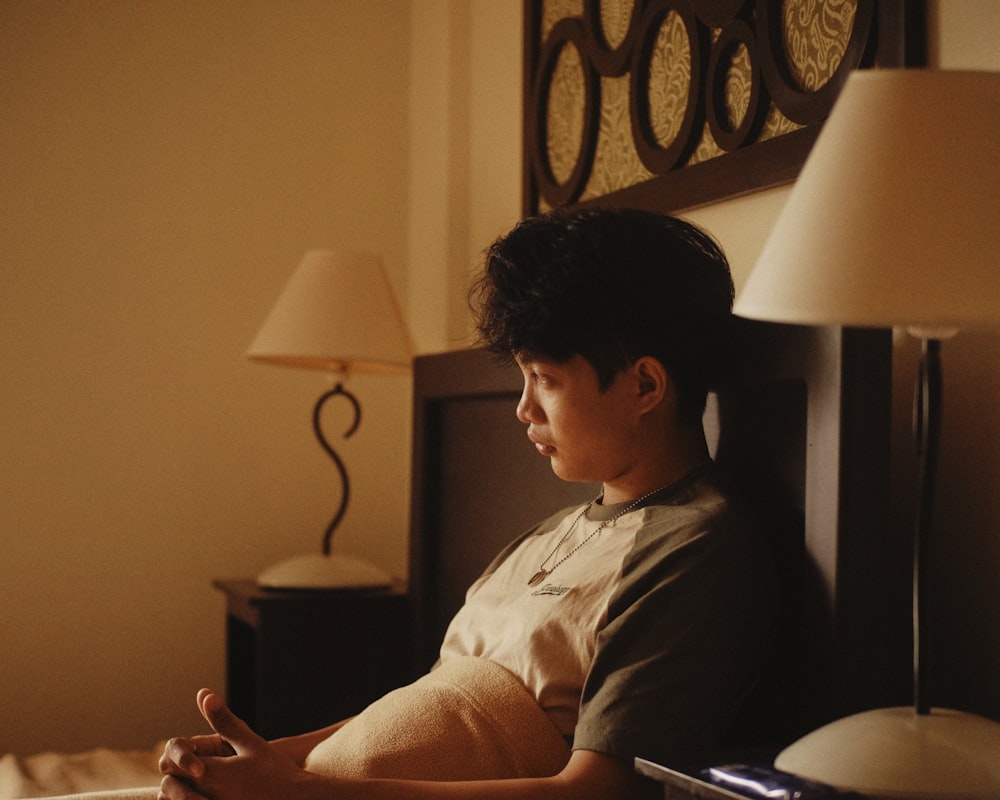 a young man sitting on a bed in a hotel room