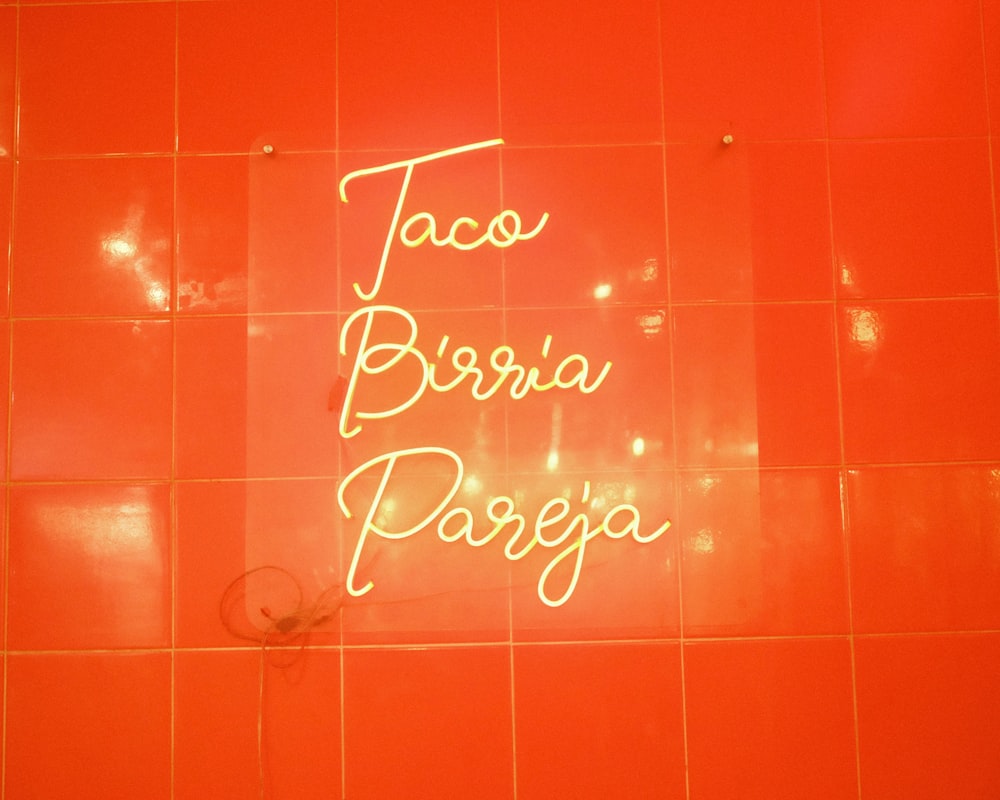 a neon sign on a tiled wall in a bathroom