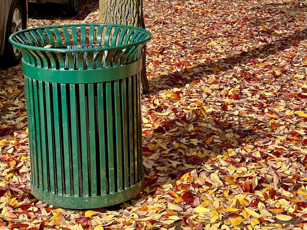 a green trash can sitting next to a tree