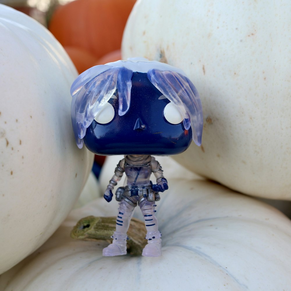 a blue and white figurine sitting on top of pumpkins