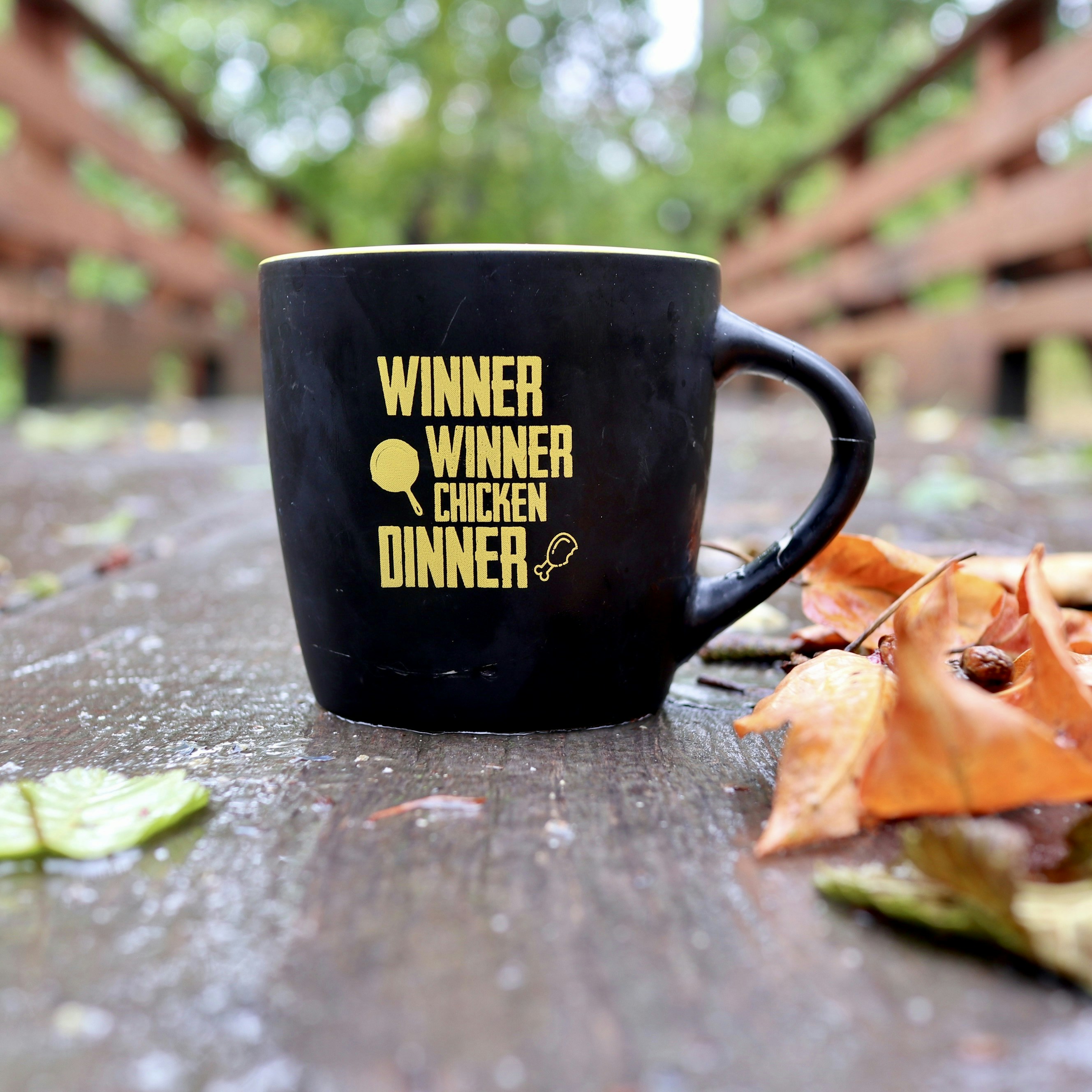 uma xícara de café preta sentada em cima de uma mesa de madeira