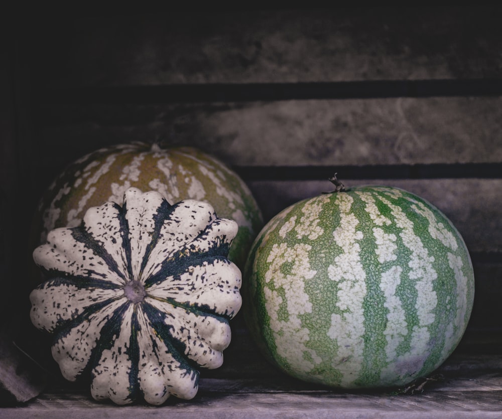 a couple of watermelons sitting on top of a wooden bench