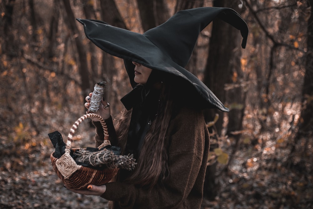 a woman wearing a witches hat holding a basket