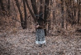 a woman in a witches costume standing in the woods