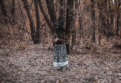 a woman in a witches costume standing in the woods