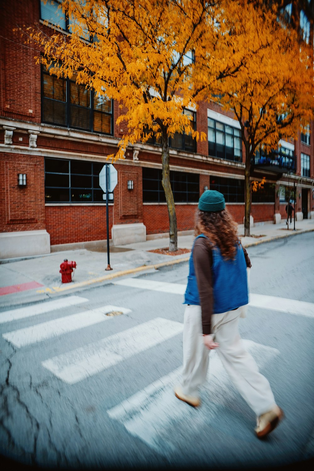 a woman crossing the street in front of a fire hydrant