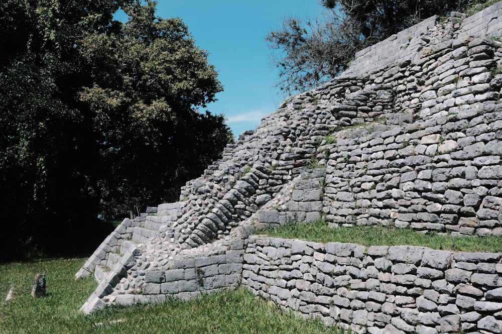 a large stone wall next to a lush green field