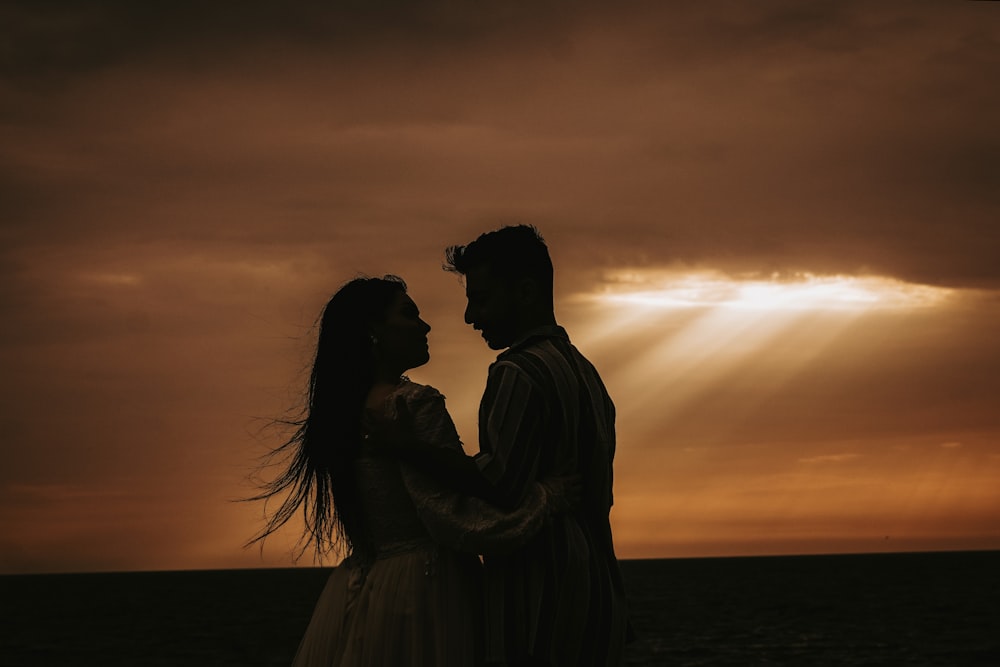 a man and a woman standing next to each other under a cloudy sky