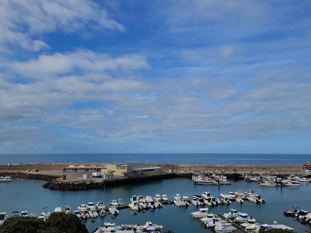 a harbor filled with lots of boats under a cloudy blue sky