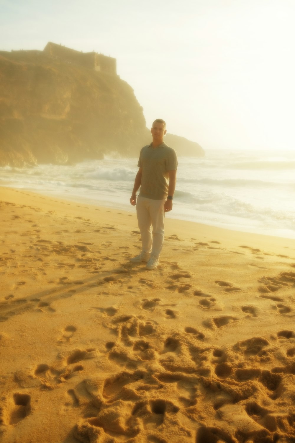 a man standing on top of a sandy beach next to the ocean