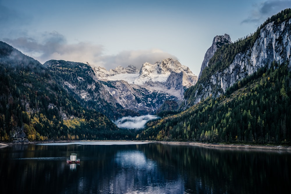 a boat floating on top of a lake surrounded by mountains