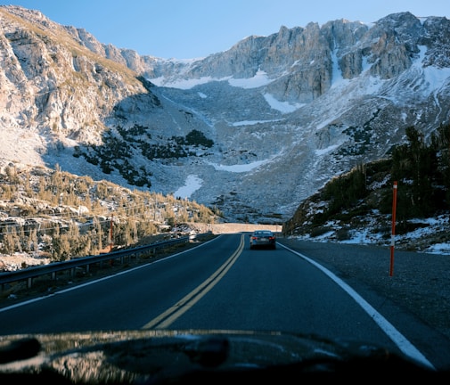 A scenic road with a car driving through mountains.
