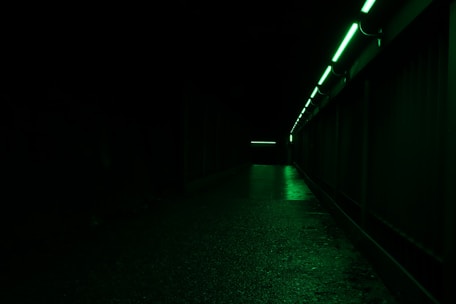 A covert rescue team navigating a dark, debris-filled space corridor illuminated by faint green digital glows.