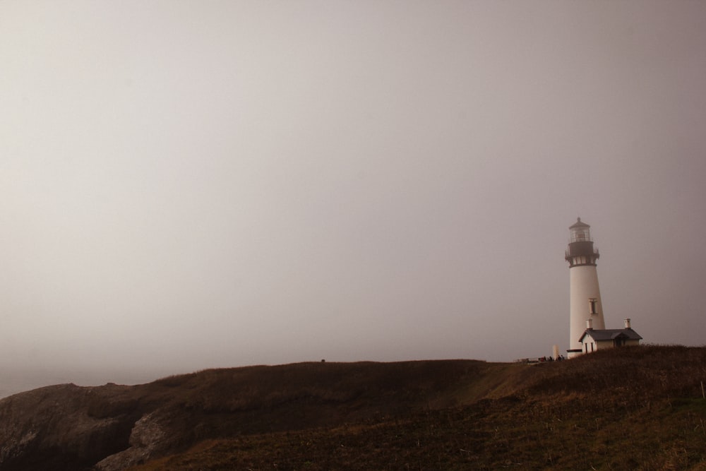 a lighthouse on a hill with a foggy sky