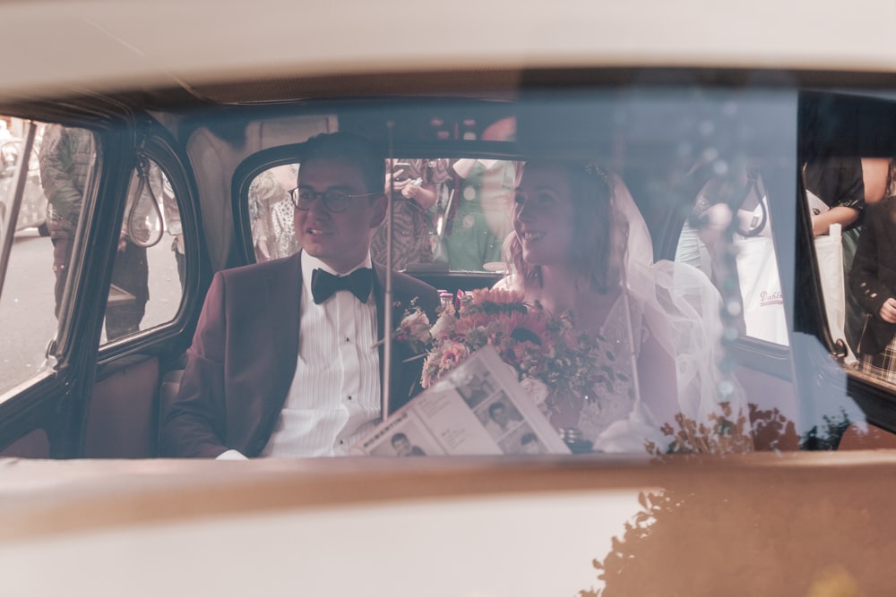 a bride and groom are sitting in the back seat of a car