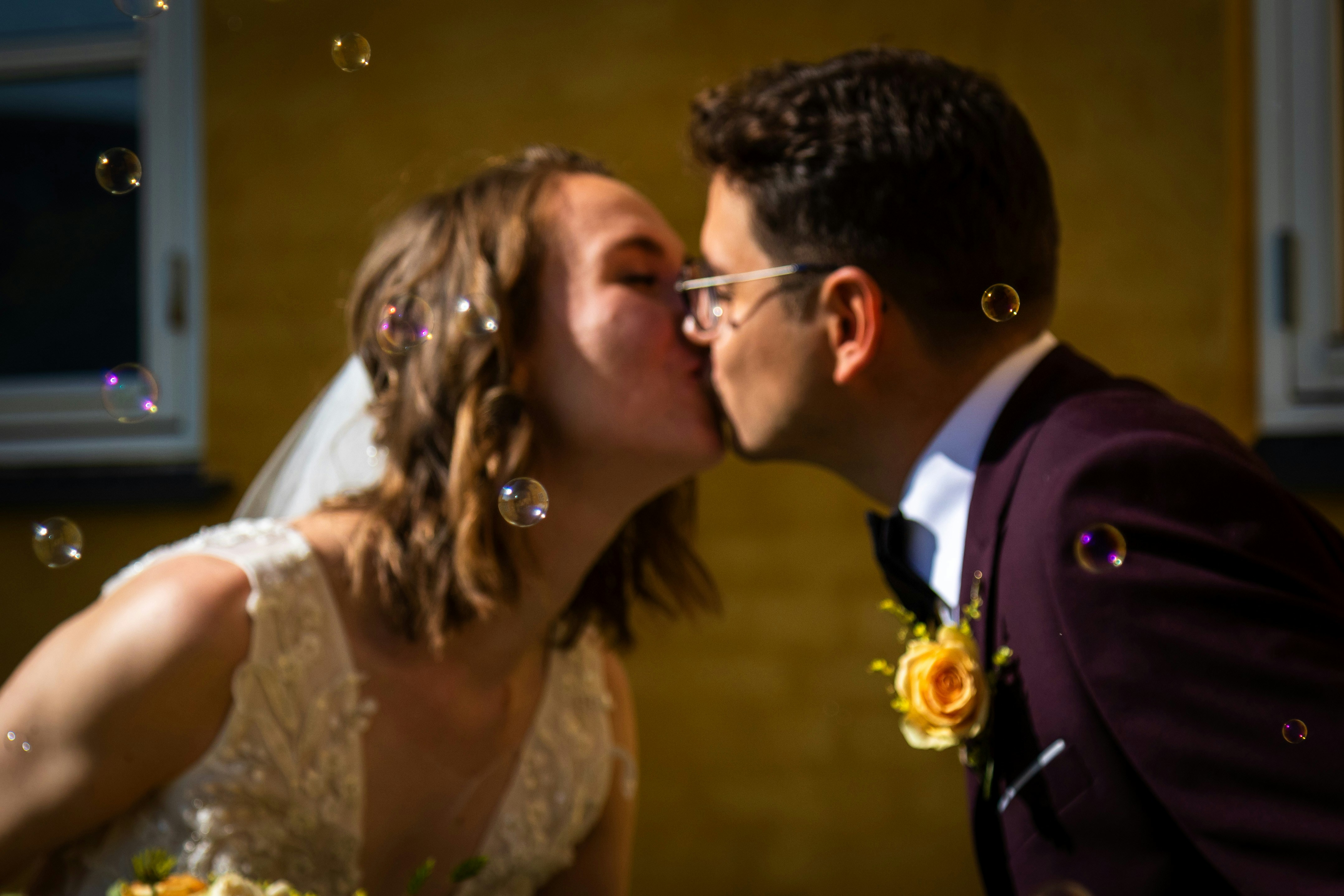 una novia y un novio besándose frente a burbujas