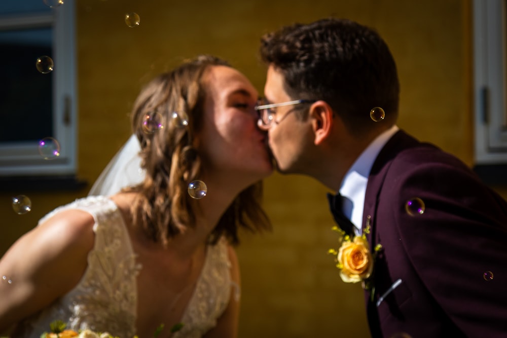 a bride and groom kissing in front of bubbles