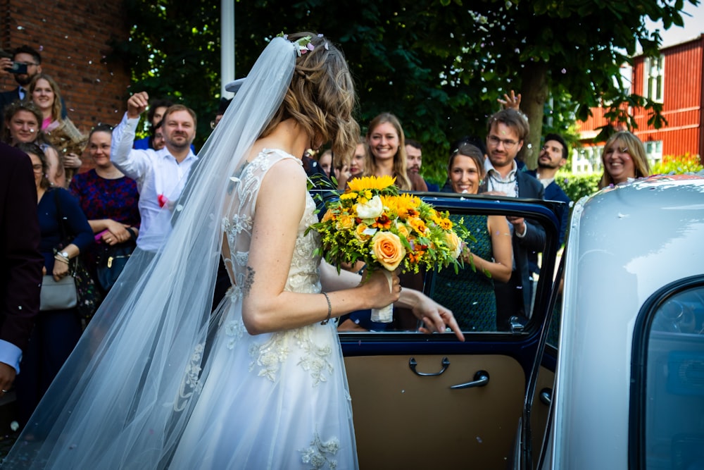 a woman in a wedding dress getting out of a car